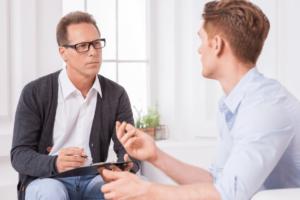un vendeur et un client en pleine discussion. Le vendeur écoute le client et prend des notes.